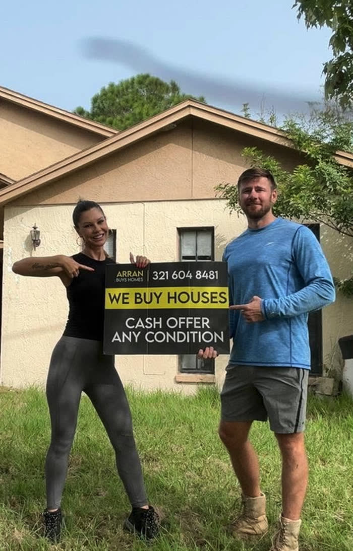 Arran and his team holding an Arran Buys Homes sign in front of a Central Florida house